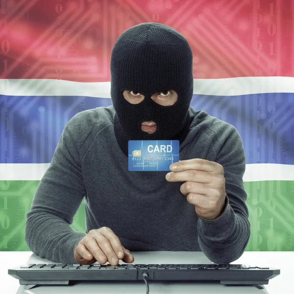 Dunkelhäutige Hacker mit Flagge auf Hintergrund mit Kreditkarte in der Hand - Gambia — Stockfoto