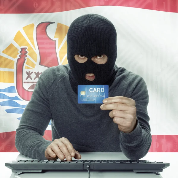 Dark-skinned hacker with flag on background holding credit card in hand - French Polynesia — Stock fotografie