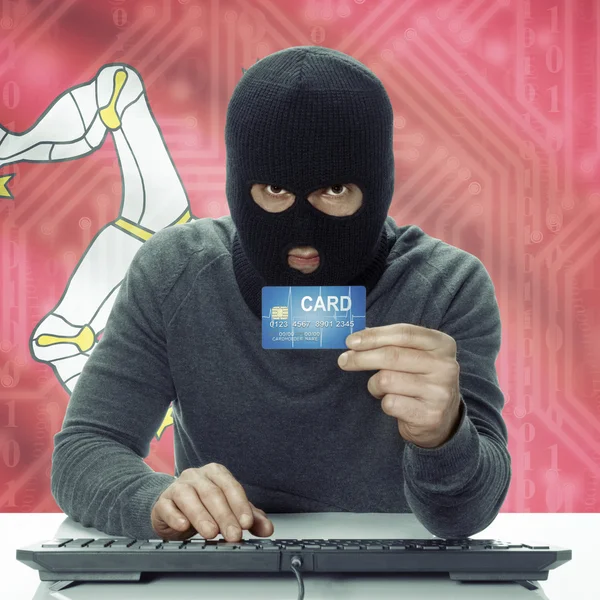 Dark-skinned hacker with flag on background holding credit card in hand - Isle of Man — Stock fotografie