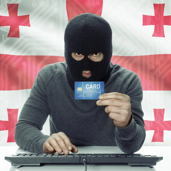 Dark-skinned hacker with flag on background holding credit card in hand - Georgia — Foto Stock