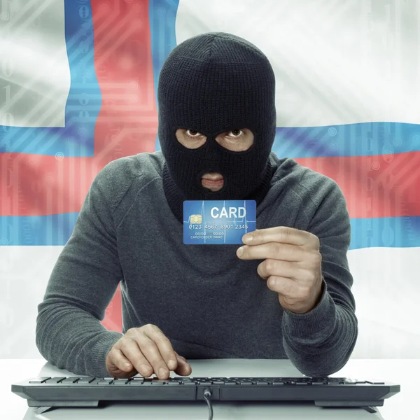 Dark-skinned hacker with flag on background holding credit card in hand - Faroe Islands — 图库照片