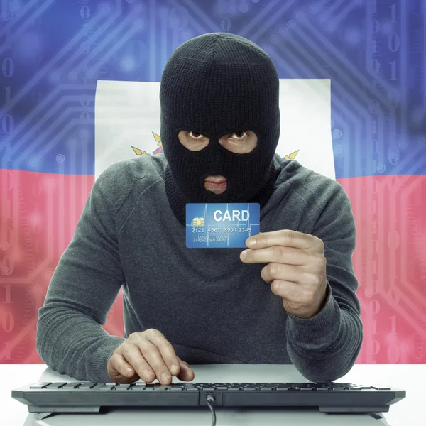 Dark-skinned hacker with flag on background holding credit card in hand - Haiti — Foto de Stock