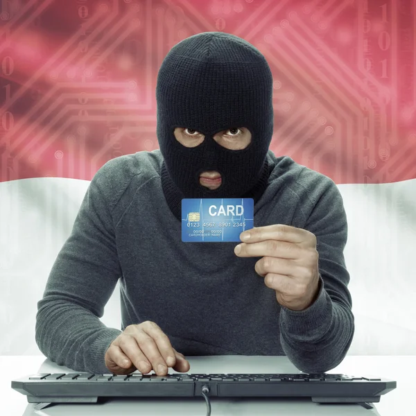 Dark-skinned hacker with flag on background holding credit card in hand - Indonesia —  Fotos de Stock