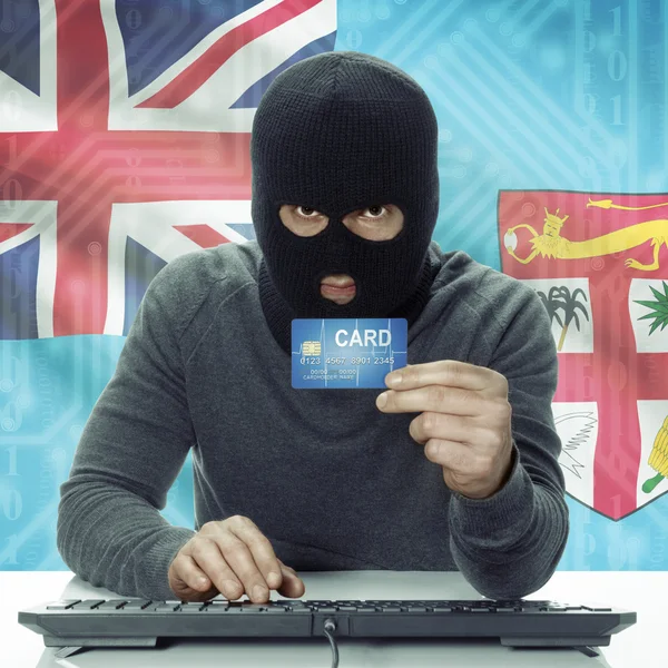 Dark-skinned hacker with flag on background holding credit card in hand - Fiji —  Fotos de Stock
