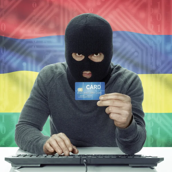 Dark-skinned hacker with flag on background holding credit card in hand - Mauritius — Zdjęcie stockowe