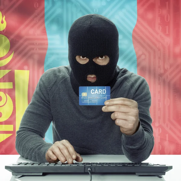 Dark-skinned hacker with flag on background holding credit card in hand - Mongolia — Stock Photo, Image