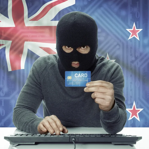 Dark-skinned hacker with flag on background holding credit card in hand - New Zealand — Stock Photo, Image