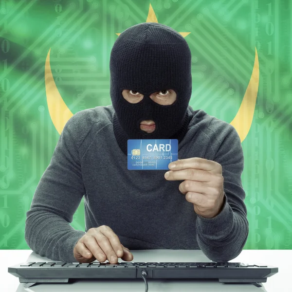 Dark-skinned hacker with flag on background holding credit card in hand - Mauritania — Stock fotografie