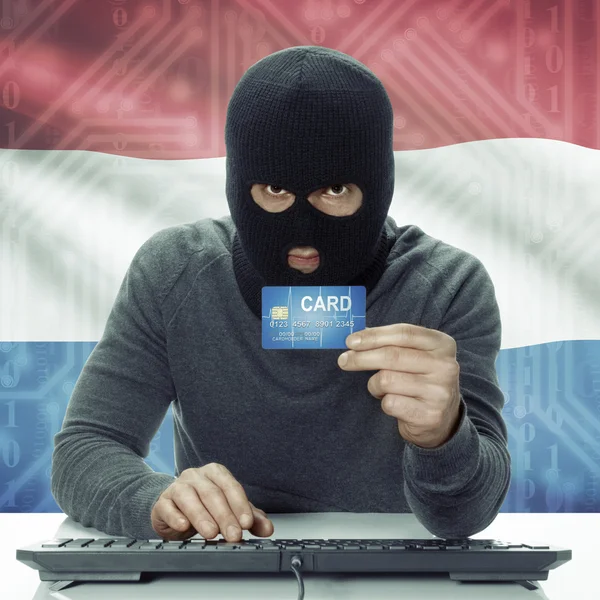 Dunkelhäutige Hacker mit Flagge auf Hintergrund mit Kreditkarte in der Hand - Niederlande — Stockfoto