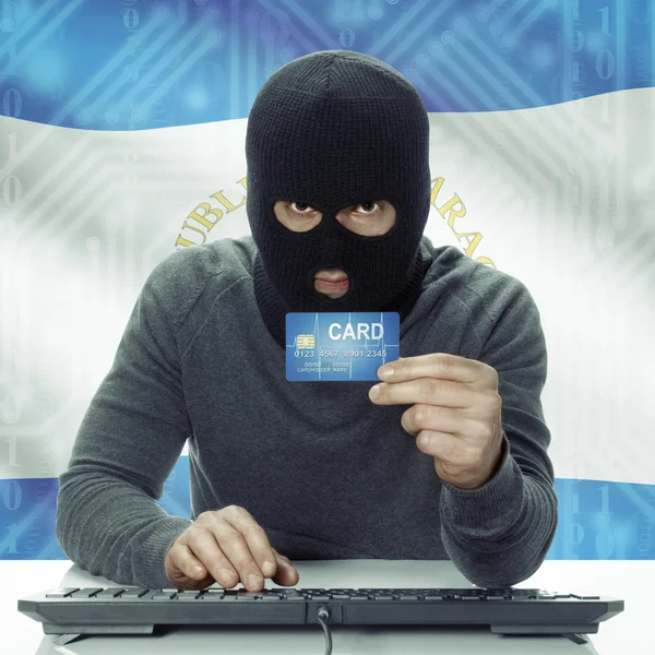 Dark-skinned hacker with flag on background holding credit card in hand - Nicaragua — Foto de Stock