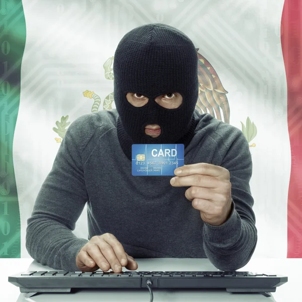 Dark-skinned hacker with flag on background holding credit card in hand - Mexico — Stock Photo, Image