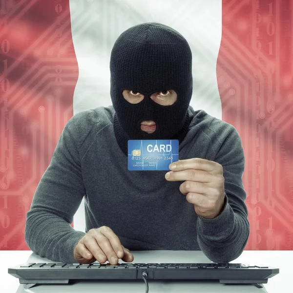 Dark-skinned hacker with flag on background holding credit card in hand - Peru — Stock fotografie