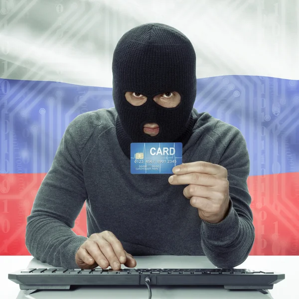 Dark-skinned hacker with flag on background holding credit card in hand - Russia — Foto de Stock