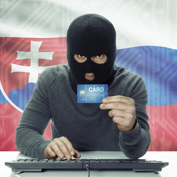 Dark-skinned hacker with flag on background holding credit card in hand - Slovakia — Zdjęcie stockowe