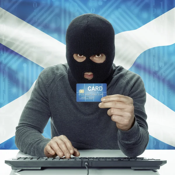 Dark-skinned hacker with flag on background holding credit card in hand - Scotland —  Fotos de Stock