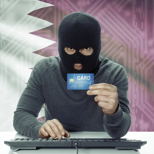 Dark-skinned hacker with flag on background holding credit card in hand - Qatar — Stock Photo, Image