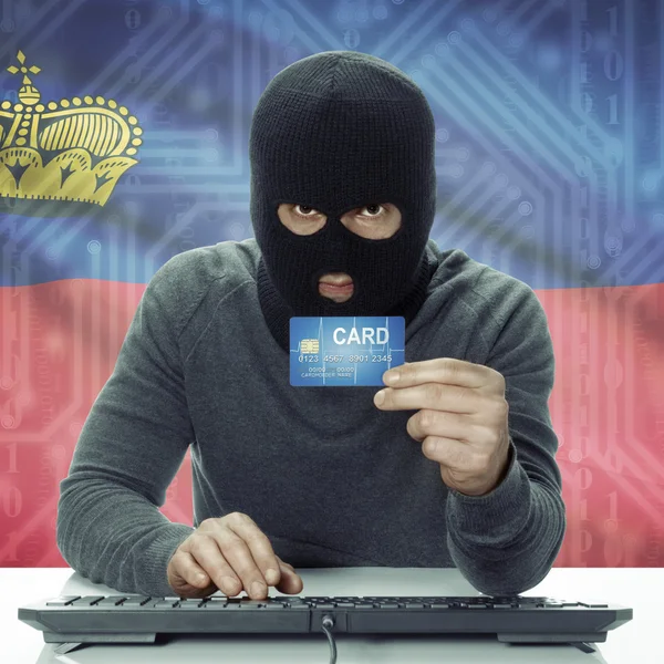 Dark-skinned hacker with flag on background holding credit card in hand - Liechtenstein — Zdjęcie stockowe