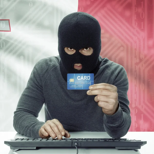 Dark-skinned hacker with flag on background holding credit card in hand - Malta — Stock fotografie