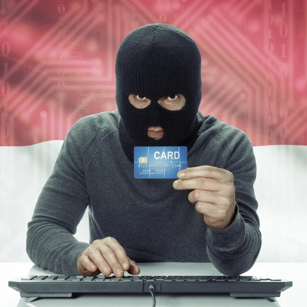 Dark-skinned hacker with flag on background holding credit card in hand - Monaco — Stock Photo, Image