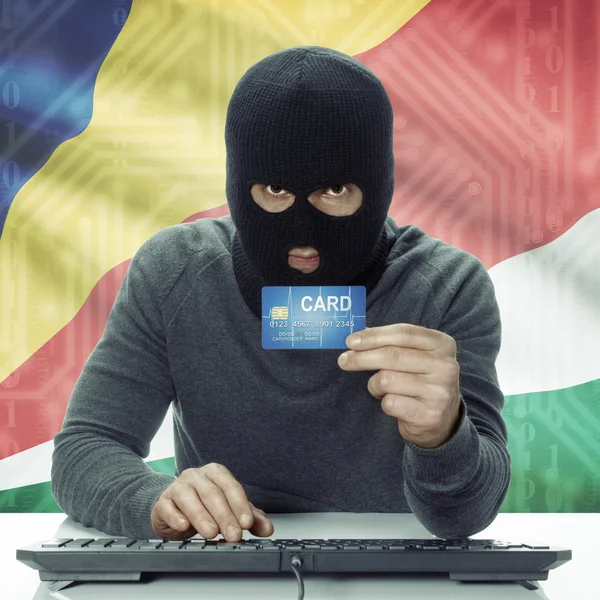 Dark-skinned hacker with flag on background holding credit card in hand - Seychelles — Zdjęcie stockowe
