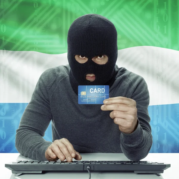 Dark-skinned hacker with flag on background holding credit card in hand - Sierra Leone — Stok fotoğraf