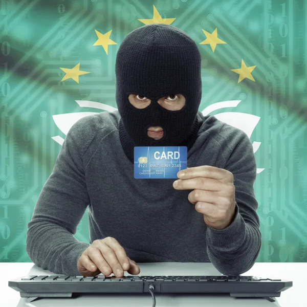 Dark-skinned hacker with flag on background holding credit card in hand - Macau — 스톡 사진