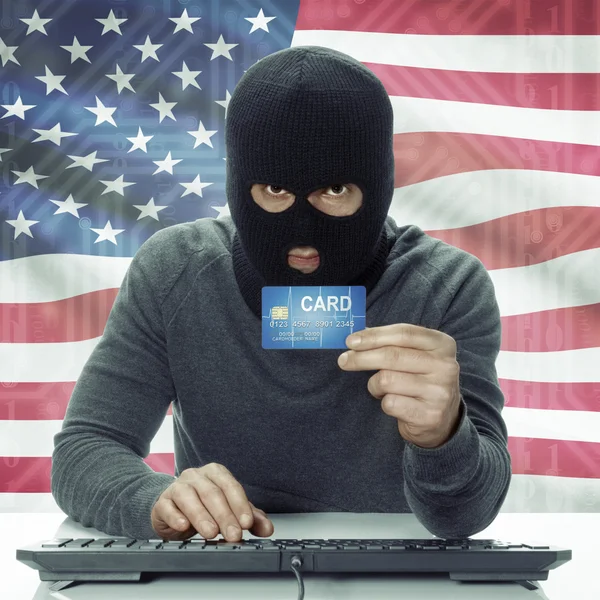 Dark-skinned hacker with flag on background holding credit card in hand - United States —  Fotos de Stock