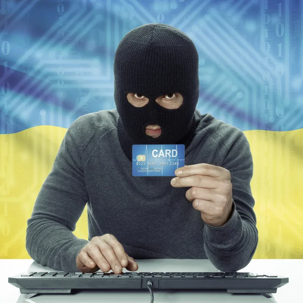 Dark-skinned hacker with flag on background holding credit card in hand - Ukraine — 图库照片