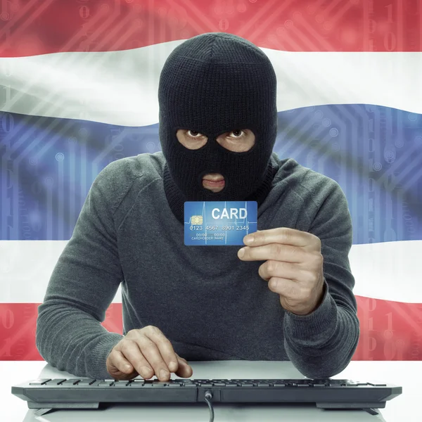 Dark-skinned hacker with flag on background holding credit card in hand - Thailand — Stock Photo, Image