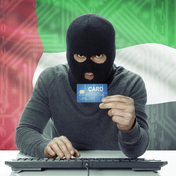 Dark-skinned hacker with flag on background holding credit card in hand - United Arab Emirates — Stock Photo, Image