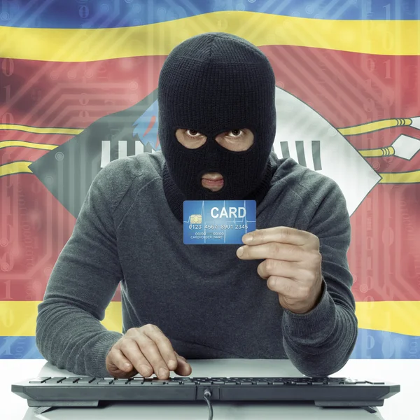 Dark-skinned hacker with flag on background holding credit card in hand - Swaziland — 图库照片