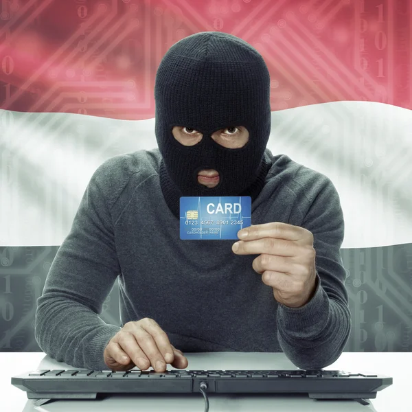 Dark-skinned hacker with flag on background holding credit card in hand - Yemen — 스톡 사진