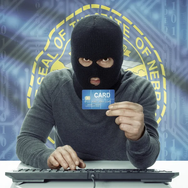 Dark-skinned hacker with USA states flag on background holding card in hand - Nebraska — Stock fotografie