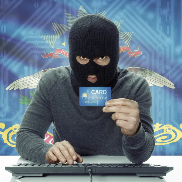 Dark-skinned hacker with USA states flag on background holding card in hand - North Dakota — Stock Photo, Image