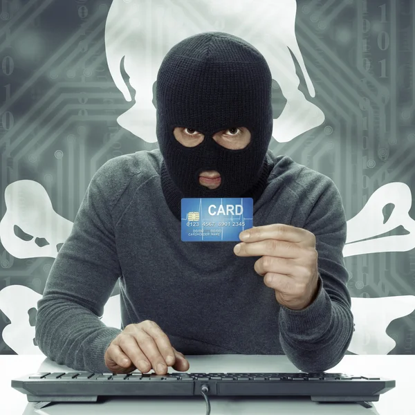 Dark-skinned hacker with flag on background holding credit card in hand - Jolly Roger — Stockfoto