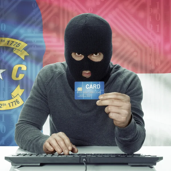 Dark-skinned hacker with USA states flag on background holding card in hand - North Carolina —  Fotos de Stock