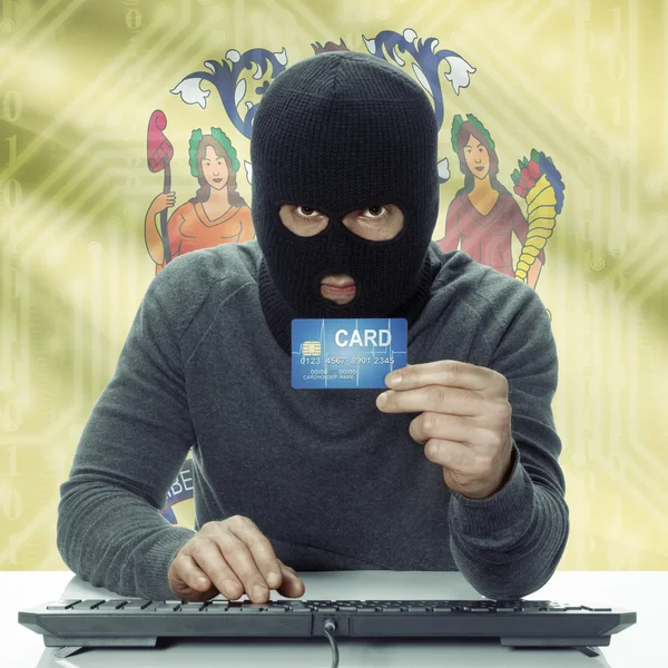 Dark-skinned hacker with USA states flag on background holding card in hand - New Jersey — Stock fotografie