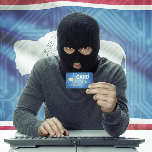 Dark-skinned hacker with USA states flag on background holding card in hand - Wyoming —  Fotos de Stock