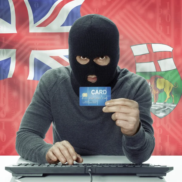 Dark-skinned hacker with Canadian province flag on background holding card - Manitoba —  Fotos de Stock