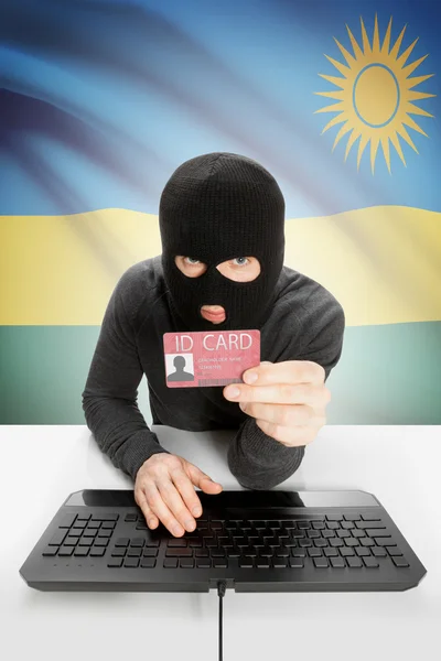 Hacker s vlajkou na pozadí držící průkaz totožnosti v ruce - Rwanda — Stock fotografie