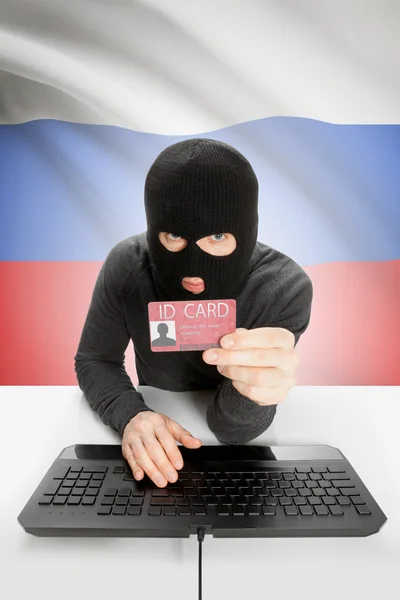 背景上有国旗的黑客手里拿着身份证-俄罗斯 — 图库照片