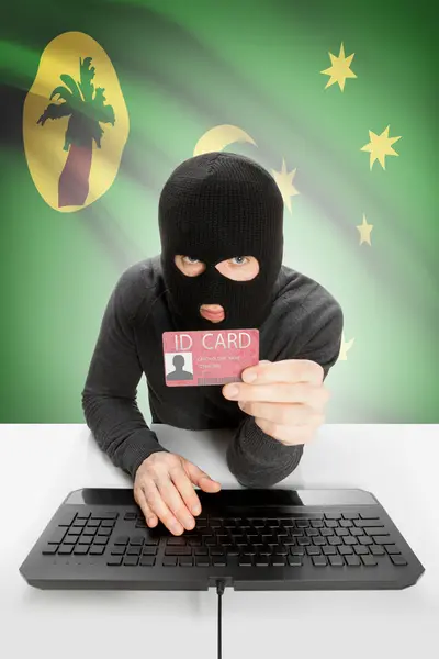 Hacker with flag on background holding ID card in hand - Cocos (Keeling) Islands — Stock Photo, Image