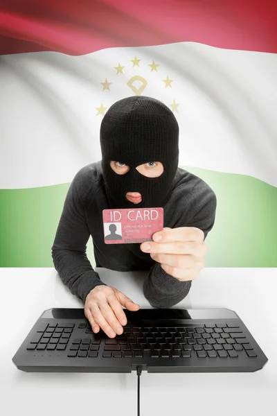 Arka planda bayrağı olan bir bilgisayar korsanı kimlik kartını elinde tutuyor - Tacikistan — Stok fotoğraf