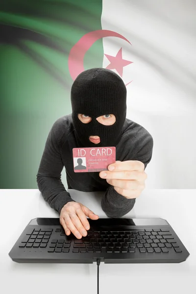 Hacker with flag on background holding ID card in hand - Algeria — Stock Photo, Image