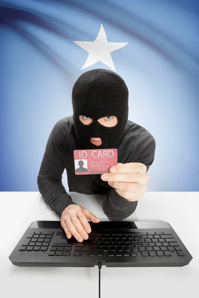 Hacker with flag on background holding ID card in hand - Somalia — Stock Photo, Image