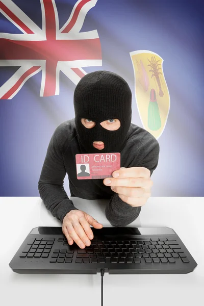 Hacker with flag on background holding ID card in hand - Turks and Caicos Islands — Stock Photo, Image