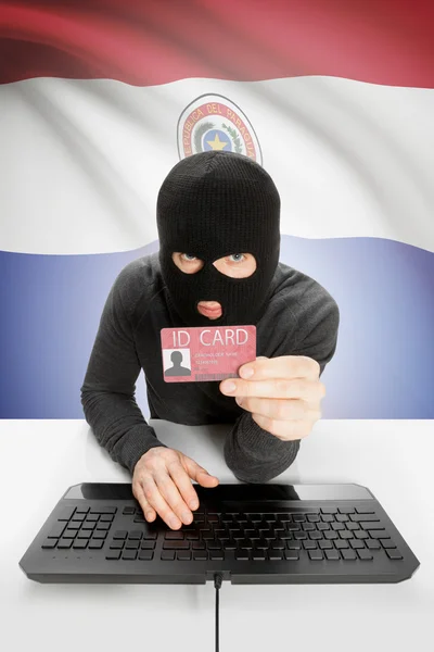 Hacker with flag on background holding ID card in hand - Paraguay — Stock Photo, Image