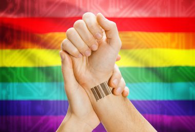 Barcode ID number on wrist and national flag on background - LGBT people