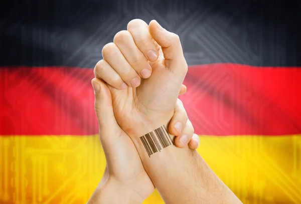 Barcode ID number on wrist and national flag on background - Germany — kuvapankkivalokuva