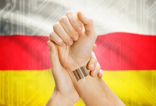 Barcode ID number on wrist and national flag on background - South Ossetia — Stockfoto